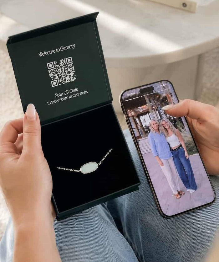 A Gemory bracelet in its gift box beside a phone showing memories